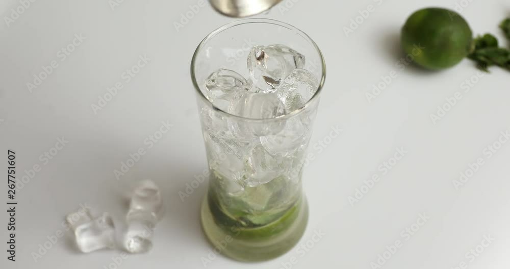 Putting liquor in jigger in glass cocktail cup with lime and mints Putting liquor in jigger in glass cocktail cup with lime and mints