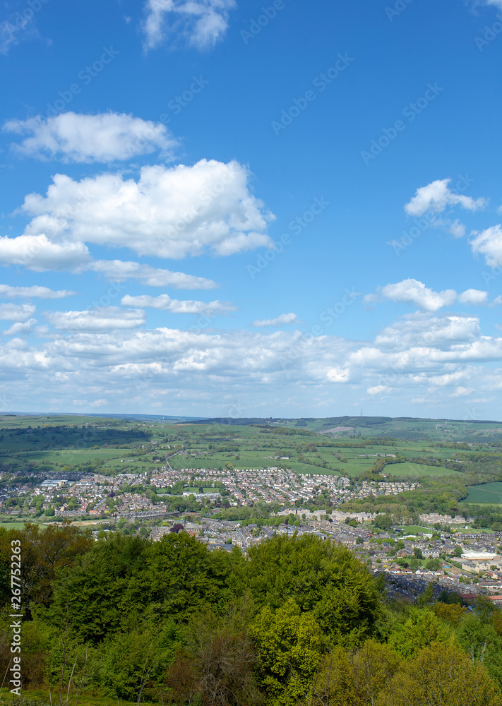 Small English town viewed from hillside set in landscape with blue sky and clouds