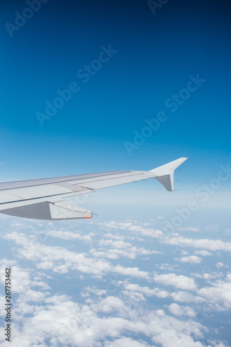 Wing of the airplane with the view of beautiful blue sky and clouds.