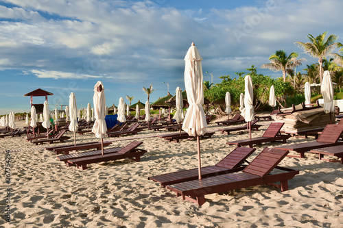 Obraz na płótnie Sun loungers and umbrellas on an empty sandy beach. Summer sunny cloudy blue sky. Kamran. Vietnam. w salonie