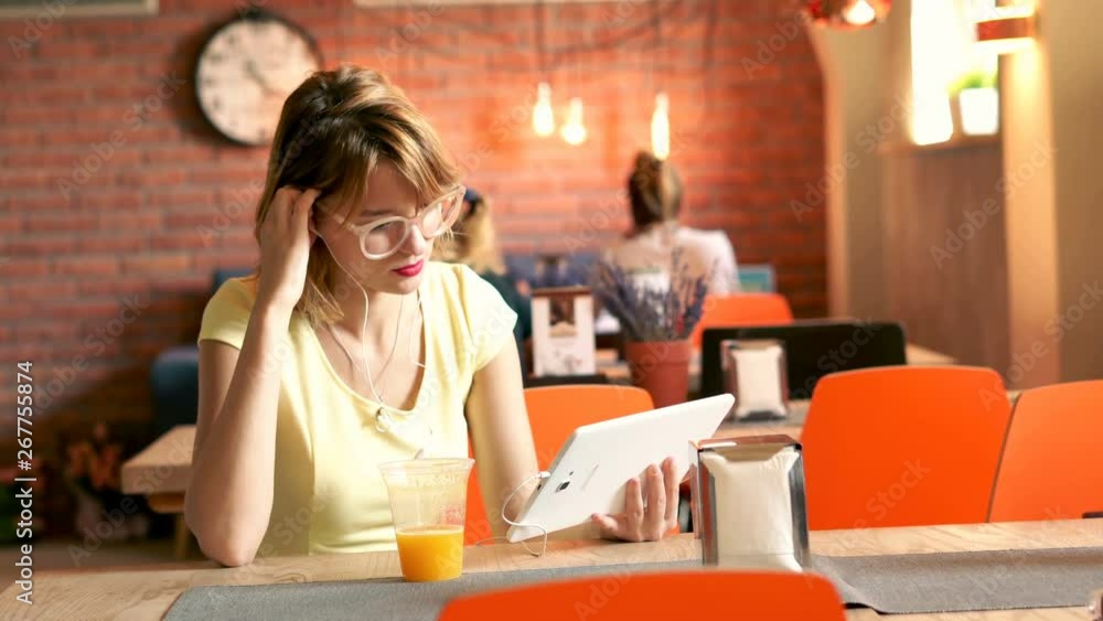 Young, pretty woman watching movie on tablet sitting in cafe, 4k Young, pretty woman watching movie on tablet sitting in cafe, 4k