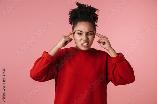 Young stressed african woman with headache posing isolated over pink wall background.