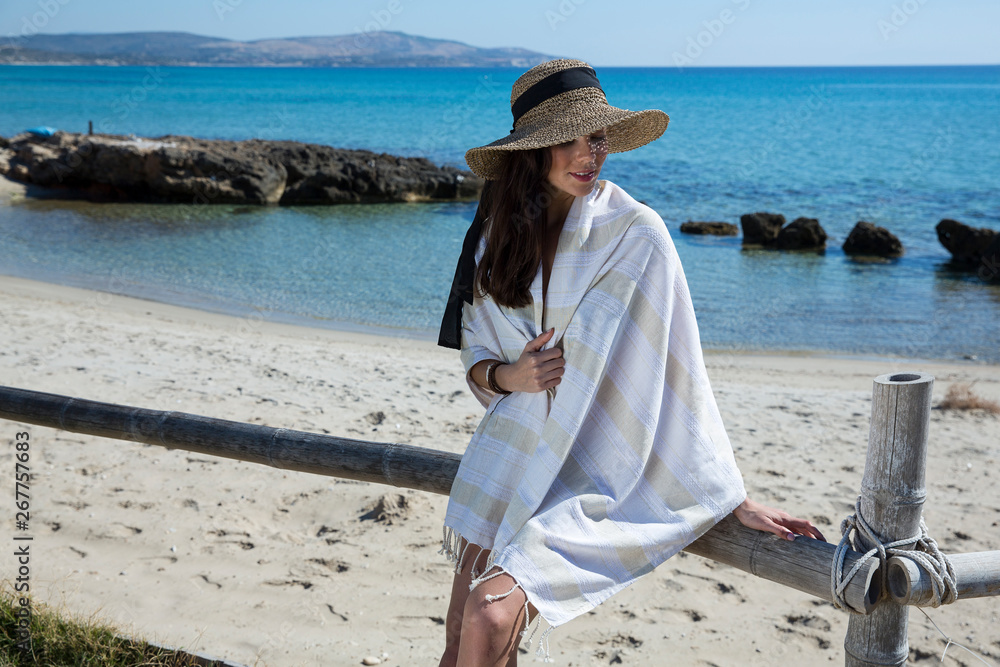 Beautiful woman in hat wrapped on beach towel by the seaside. Summer and holiday concept - Image