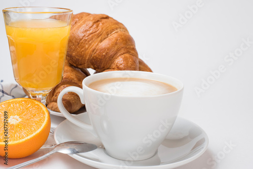 Breakfast coffee with croissants and orange juice on a white background. Latte on a saucer and cellular cotton towel