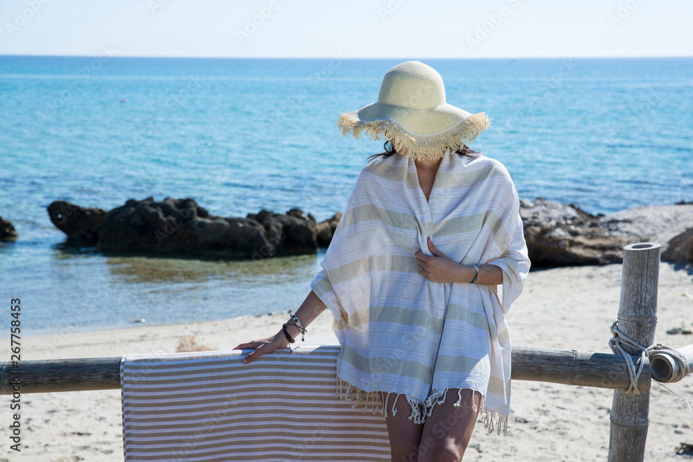 Beautiful woman in hat wrapped on beach towel by the seaside. Summer and holiday concept - Image
