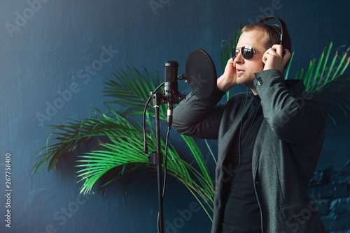 Close up of a man singer in a headphones recording a song in a home studio photo