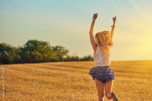 Cute young woman jumping in a wheat field.