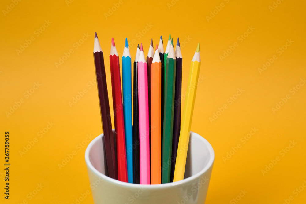 Fototapeta premium Back to school. Children's creativity. Color pencils in a glass on a yellow background