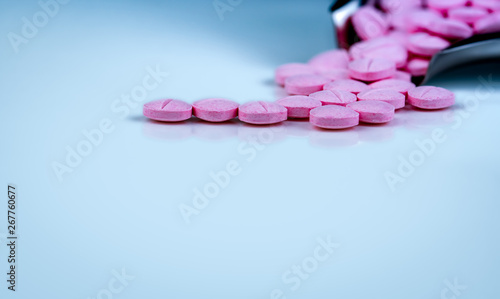 Pink tablets pills on blurred background of drug tray. Pharmaceutical industry. Pharmacy products. Vitamins and supplements. Medication use in hospital or drugstore. Global drug retail market.