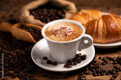 A cup of cappuccino with coffee bean as background.