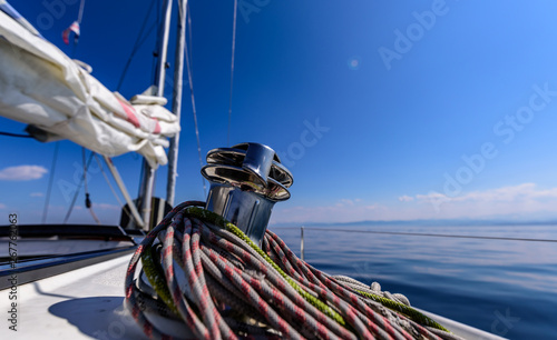 Winch on a sailboat with a lot of ropes around it.