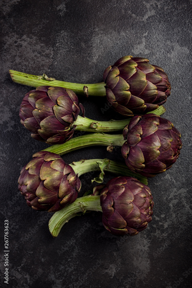 Purple artichokes flowers heads on dark slate Purple artichokes flowers heads on dark slate