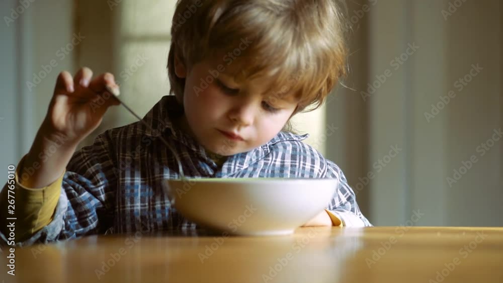 Cute baby eating. Little boy having breakfast in the kitchen. Happy baby boy spoon eats itself. Baby eating food on kitchen. Cute baby eating. Little boy having breakfast in the kitchen. Happy baby boy spoon eats itself. Baby eating food on kitchen.