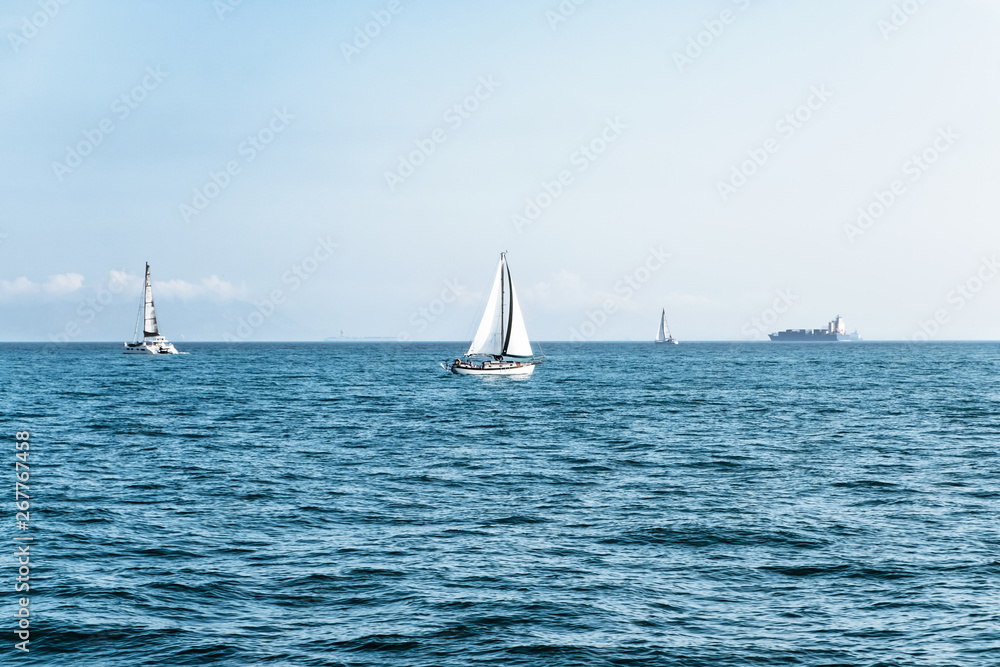 Luxury yachts in open sea at beautiful sunny day. Active lifestyle for active people. Tropical vacation. Weekend getaway from city. Natural landscape. Horizontal image with space for text and design.