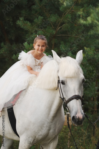 happy little princess on white horse in the forest
