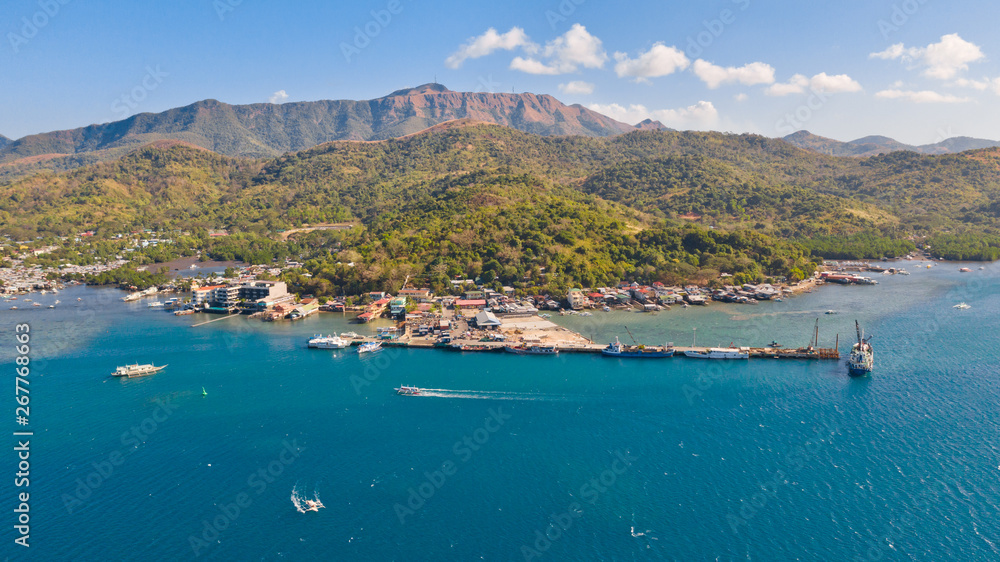 A small seaport in the City of Coron, Philippines.Big island with hills and town, view from above.Cargo ships and boats at the pier.Philippines, Palawan