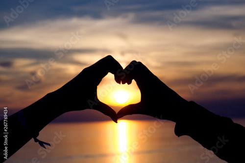 Two hands in heart shape against the sun book cover