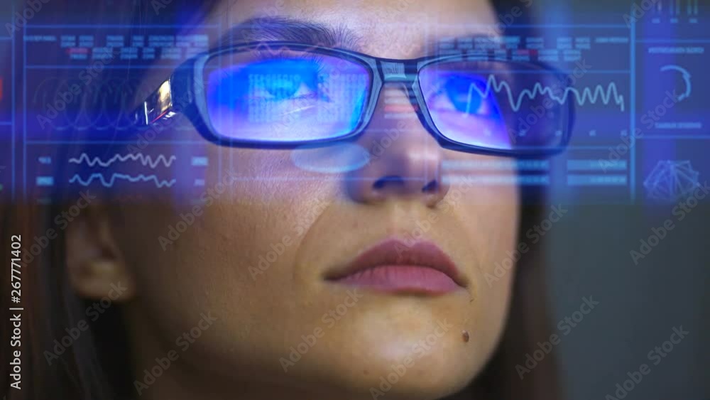 The businesswoman in glasses looking on a screen on the hologram background The businesswoman in glasses looking on a screen on the hologram background