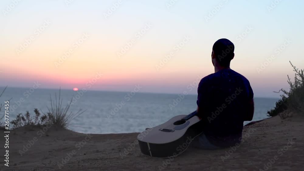 Cinematic Silhouette of young man outdoors playing acoustic guitar at sunset Cinematic Silhouette of young man outdoors playing acoustic guitar at sunset