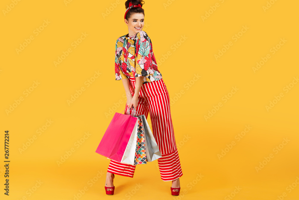 Full lenhts photo of young happy caucasian woman in casual colorful clothes holding bags and shopping over orange background. Shopping and sales concept. Full lenhts photo of young happy caucasian woman in casual colorful clothes holding bags and shopping over orange background. Shopping and sales concept.