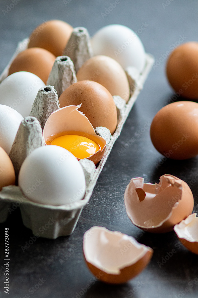 Fresh organic raw eggs, white, beige and brown, one is cracked Fresh organic raw eggs, white, beige and brown, one is cracked