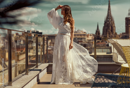 Beautiful young bride in white wedding dress posing outdoor over city view photo