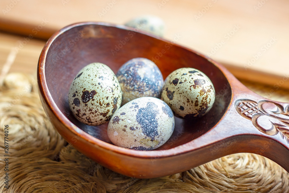 Fresh raw quail eggs in wooden spoon on rustic straw and wooden vintage background. Fresh raw quail eggs in wooden spoon on rustic straw and wooden vintage background.