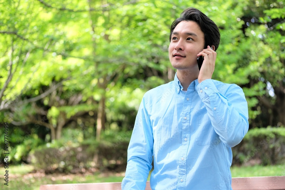 公園でスマホ　携帯を操作する三十代男性