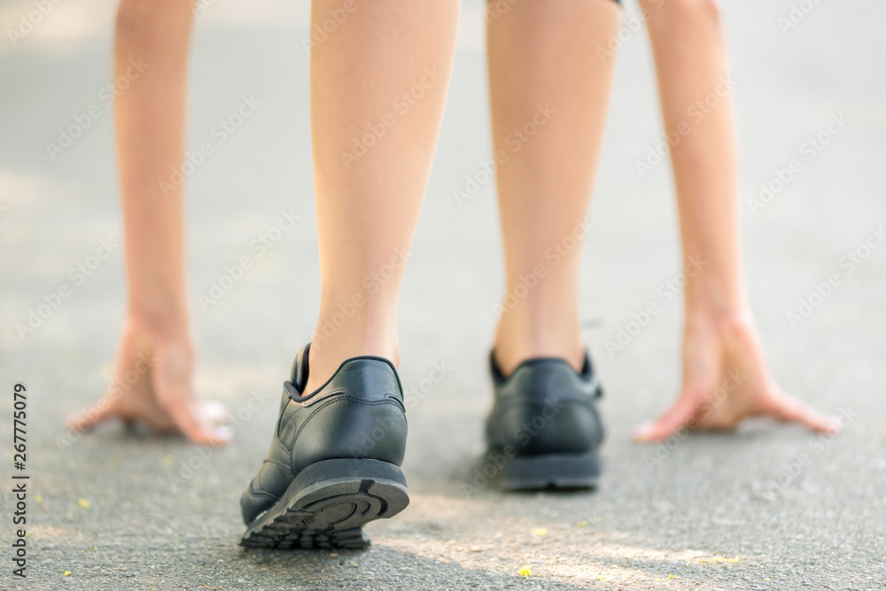 Female legs and hands put on the asphalt close-up, symbol of the start before the run, strong personality and marathon run