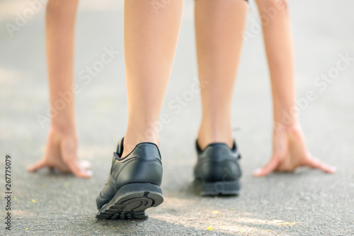 Female legs and hands put on the asphalt close-up, symbol of the start before the run, strong personality and marathon run