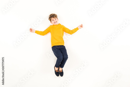 top view of scared kid looking at camera while flying on white