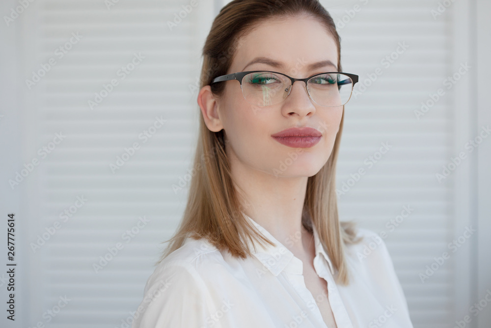Portrait of a young stylish business woman in a white shirt and glasses. Portrait of a young stylish business woman in a white shirt and glasses.