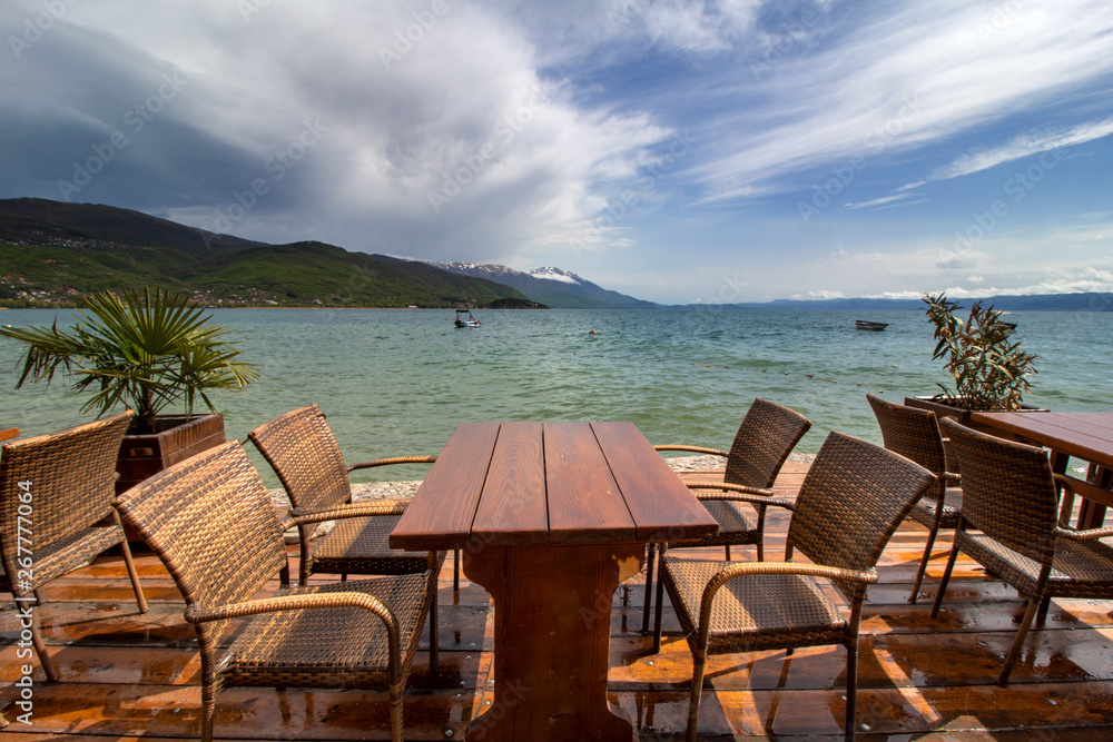 A look through the wet tables and chairs. The stunning sky above Ohrid Lake after the rain. Against the mountain hills.