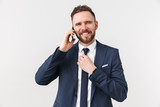 Happy young handsome businessman posing isolated over white wall background talking by mobile phone.