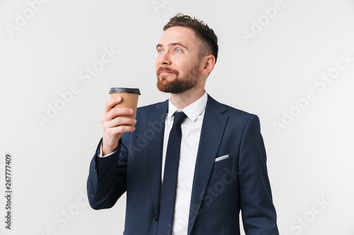 Businessman posing isolated over white wall background drinking coffee. © Drobot Dean