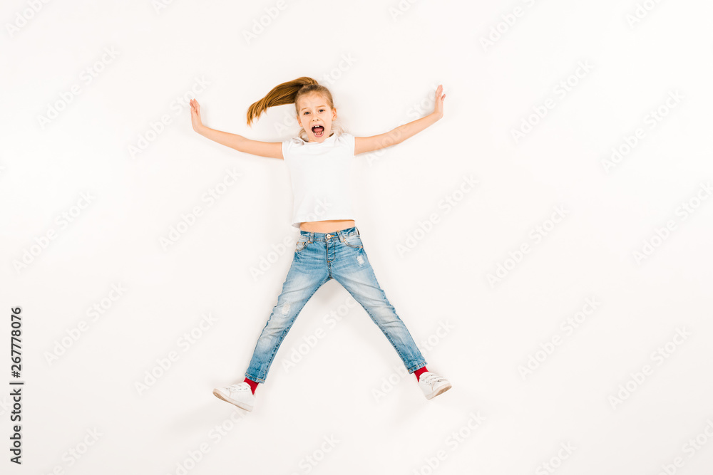 top view of scared kid screaming while lying on white top view of scared kid screaming while lying on white