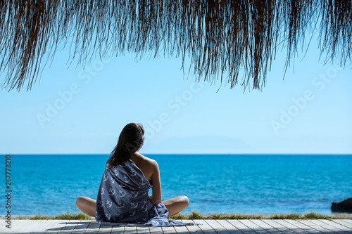 The girl sits on the beach and looks at the sea.