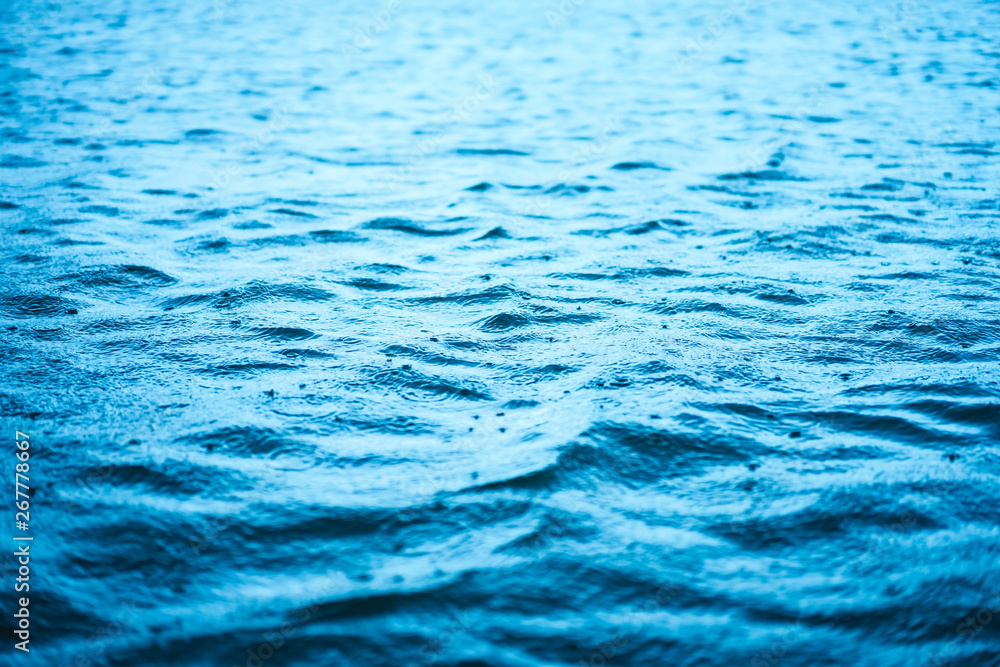 Naklejka premium Close up surface of wave blue sea with rain drops abstract background.