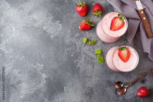 Homemade yogurt with fresh strawberries in glasses on a dark concrete background. Selective focus. Copy space.