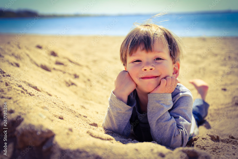 Ein dreijähriger Junge liegt im Sand Ein dreijähriger Junge liegt im Sand