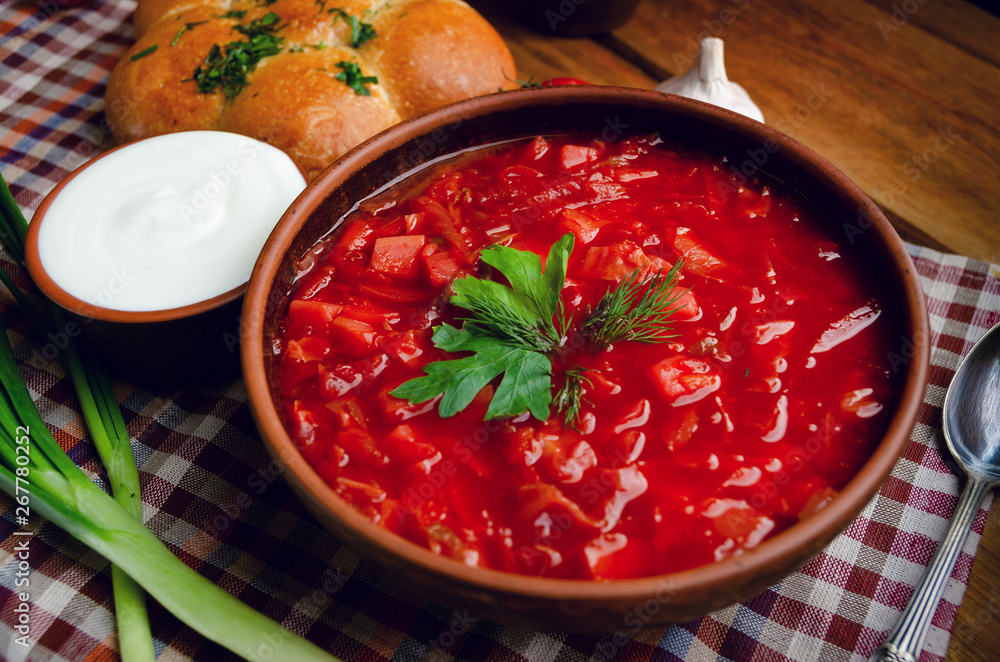 Ukrainian national cuisine - red borsch with donuts in a clay bowl on a wooden table. Ukrainian national cuisine - red borsch with donuts in a clay bowl on a wooden table.
