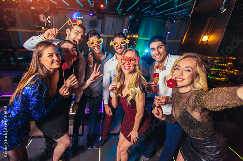 Group of friends partying in a nightclub make selfie photo