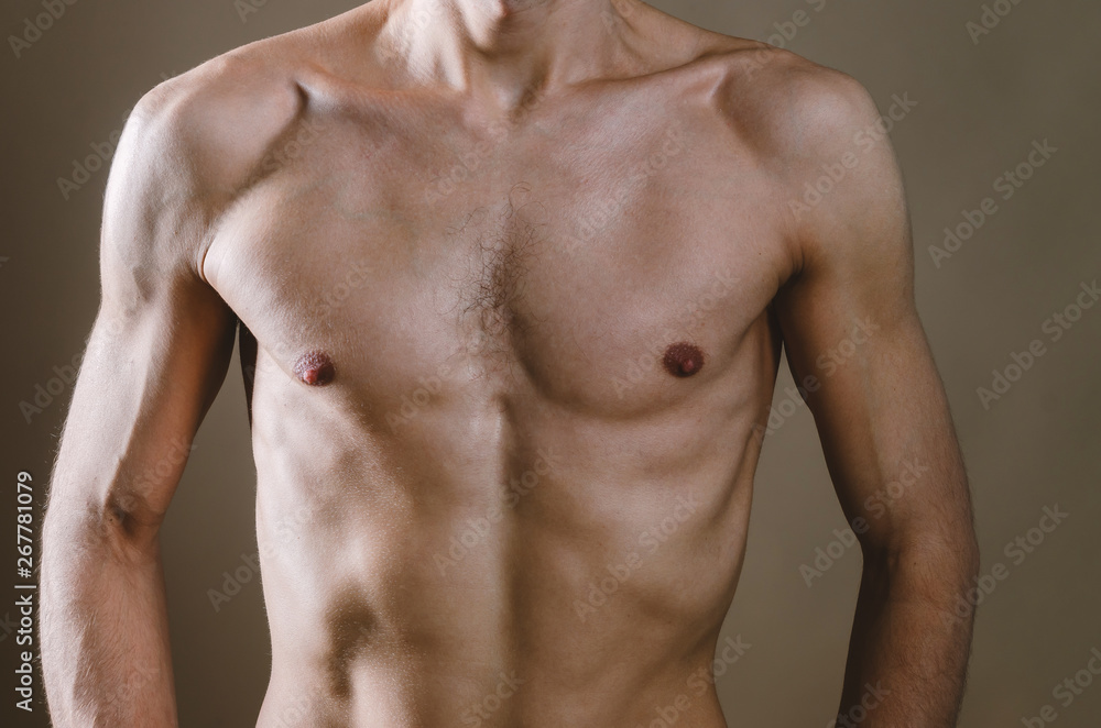 Naked torso of a young, slim, pumped-up man on a beige background. Tight naked attractive man in black jeans. Naked torso of a young, slim, pumped-up man on a beige background. Tight naked attractive man in black jeans.