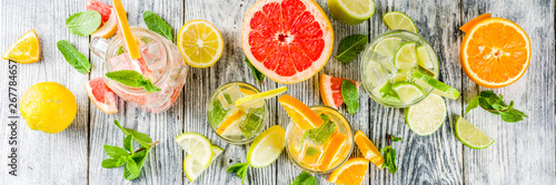 Summer refreshment drinks. Four types of citrus lemonade or mojito cocktail - orange, lime, lemon, pink grapefruit. Infused citrus water. On a wooden white background,