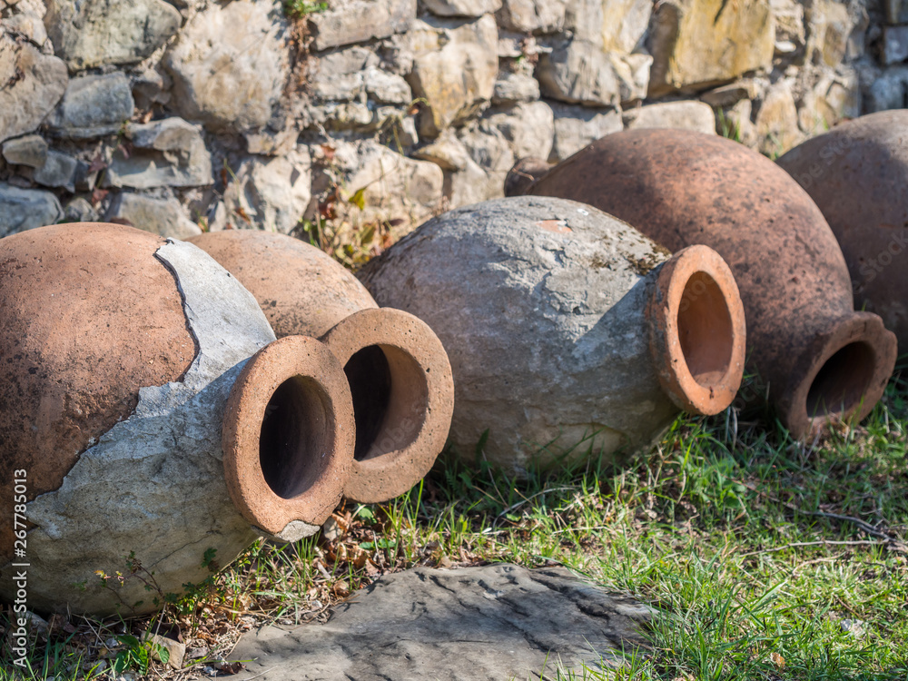 Old kvevris (qvevris) in front of the Ikalto cathedral, Kakheti, Georgia. Kvevri is a large earthenware vessel used for the fermentation and storage of wine, often buried below ground level.
