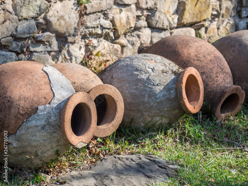 Obraz na płótnie Old kvevris (qvevris) in front of the Ikalto cathedral, Kakheti, Georgia. Kvevri is a large earthenware vessel used for the fermentation and storage of wine, often buried below ground level. w salonie