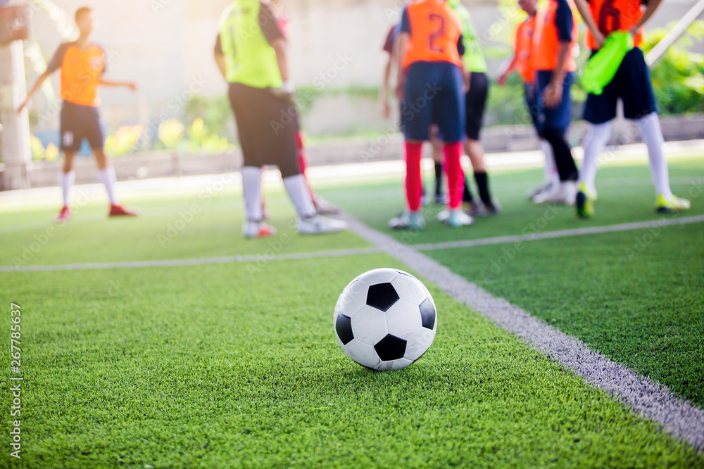 soccer ball on green artificial turf with blurry soccer players