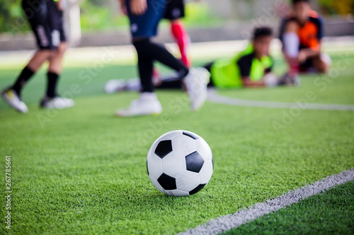 Fototapeta Naklejka Na Ścianę i Meble -  soccer ball on green artificial turf with blurry soccer players standing