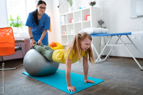 Active little blonde patient exercising on pilates ball
