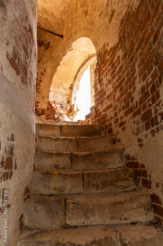 Old brick staircase in the bell tower. The light from the open window
